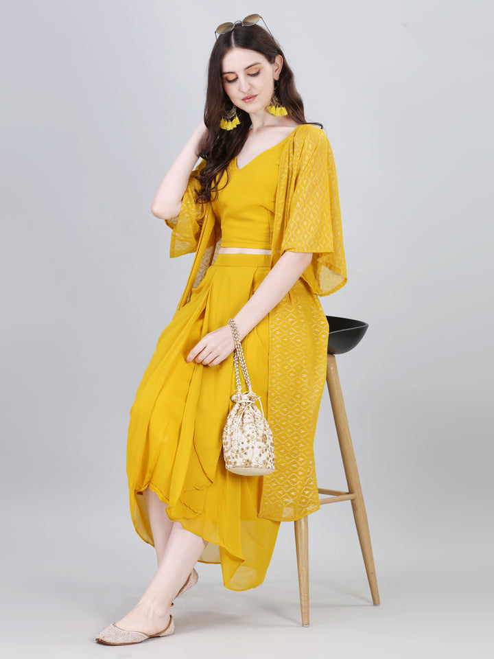 Woman wearing mustard yellow draped skirt co-ord set with crop top and long shrug, holding potli bag – Modestouze Attires