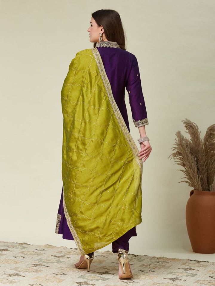 Woman wearing a green saree with a purple blouse against a neutral background