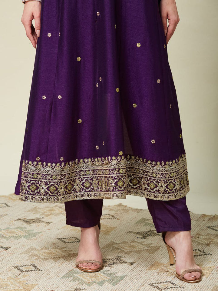Purple traditional outfit with gold embroidery on a neutral background